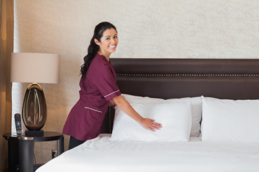 Happy hotel maid at work in hotel room